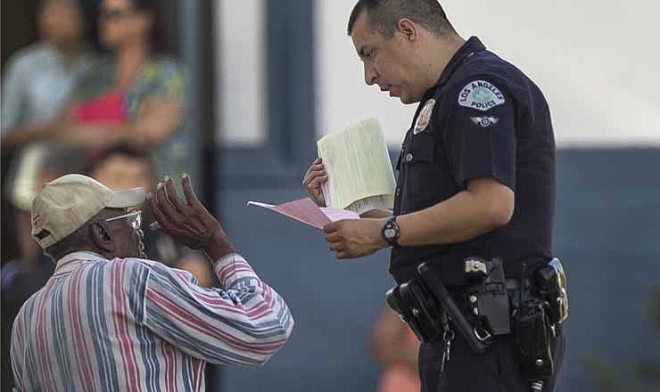 In this photo taken Wednesday, Aug. 29, 2012, senior driver Preston Carter, 100, holds onto his California driver's license and car keys, as he talks with Los Angeles police officer, after police say his car went onto a sidewalk and plowed into a group of parents and children outside a South Los Angeles elementary school. There is no upper age limit for driving a car in California. 