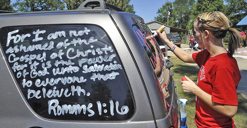 Kountze High School cheerleader Brooke Coates paints scripture verses on a car Wednesday in Kountze, Texas. The small Hardin County community is rallying behind the high school's cheerleaders after the squad members were told they could not use scripture verses on their signs at the football games. 