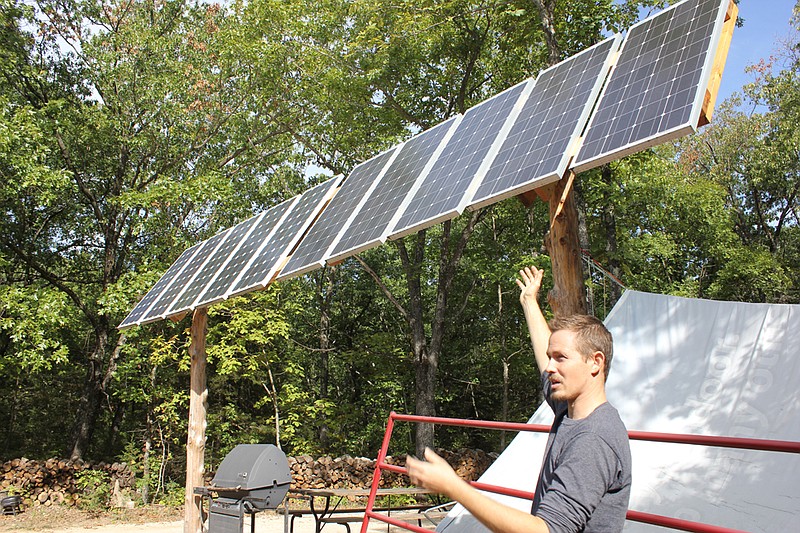 Tao Weilundemo shows off the solar panels that collect sunlight bouncing off of the metal roof of the common building at Maya Creek. Maya Creek's residents harvest solar energy to be stored in golf cart batteries, which powers cell phones, low-wattage LED light bulbs, efficient laptops and other electronic necessities.