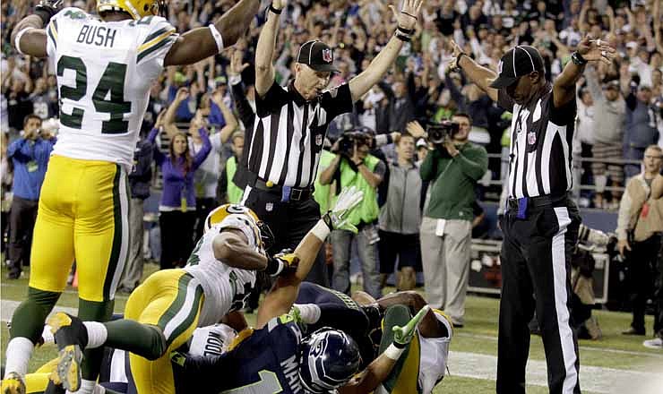 One official (left) signals a touchdown by Seattle Seahawks wide receiver Golden Tate (obscured) on the last play of their game against the Green Bay Packers Monday in Seattle. The other official (right) did not signal a touchdown. The touchdown ruling prevailed. Controversy over the referees' contradictory calls centered around who had possession as the Seahawks receiver and a Green Bay defender fought for the ball. The Seahawks won 14-12.