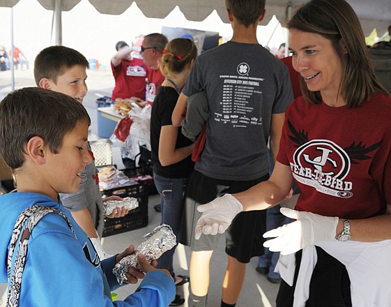 Alex Burkhead, far, and Reese Dodson, near, pick up some wieners from Andrea Howerton at Central Bank's Jay Fan Tailgate before Friday's game against Hickman at Adkins Field. Jefferson City school officials are expected to announce the location chosen for a new high school campus Monday.