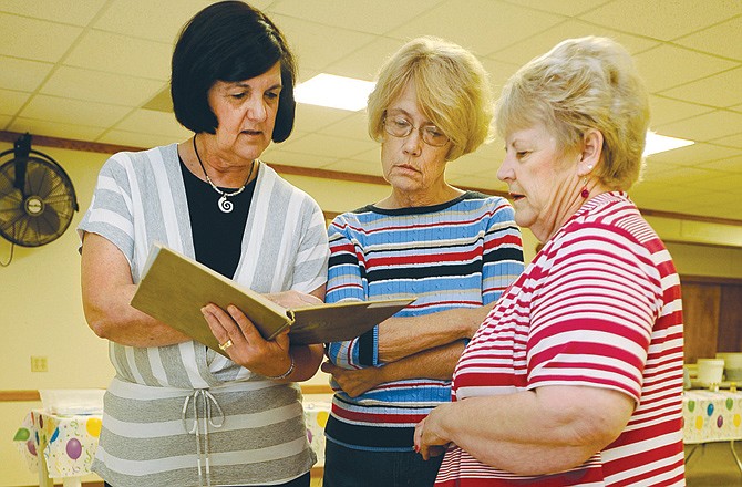 Former classmates (from left) Cathy Wolters, Pat Tracy and Helen Ferguson peruse some of their high school yearbooks during a Fatima Class of 1965 65th birthday party at the Westphalia Lions Club on Saturday. 