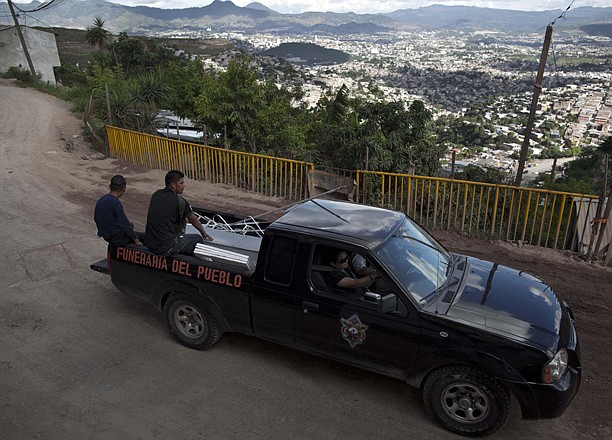 Charity employees from the Funeraria del Pueblo, or People's Mortuary, transport the remains of murder victim Marvin Adalid Membreno, 19, as his relatives ride in the truck bed next to his coffin from the morgue to a church to hold a wake Aug. 17 in Tegucigalpa, Honduras. The charities that provide the coffins, and sometimes free transportation and soft drinks to the bereaved, are run using public funds by three elected officials.