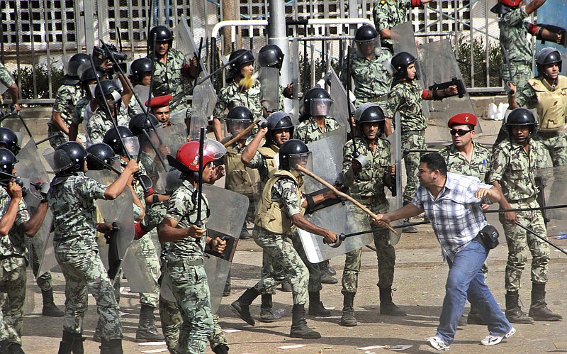 A protester, right, waves a stick at Egyptian soldiers during clashes outside the Ministry of Defense in Cairo, Egypt. Amnesty International warned Tuesday that the practice of impunity for Egyptian police and military continued even after regime change and Hosni Mubarak's ouster, and urged the country's newly elected leader to deal with this "bloody legacy" by bringing to justice those responsible for killing, maiming and abusing protesters.