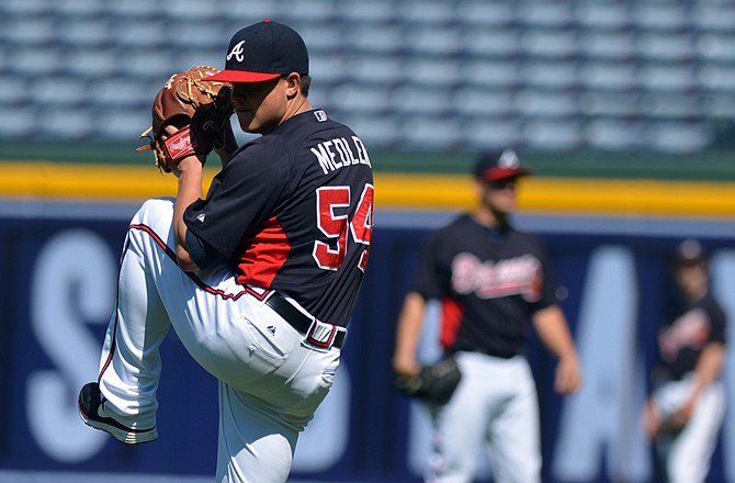 Braves pitcher Kris Medlen warms up in the outfield during practice Thursday in Atlanta.