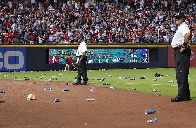 Atlanta Braves officials pick up trash on the field as security stand by during the eighth inning of the National League wild card playoff game against the St. Louis Cardinals on Friday in Atlanta. The Cardinals won baseball's first wild-card playoff, taking advantage of a disputed infield fly call that led to a protest and fans littering the field with debris to defeat the Braves 6-3. 
