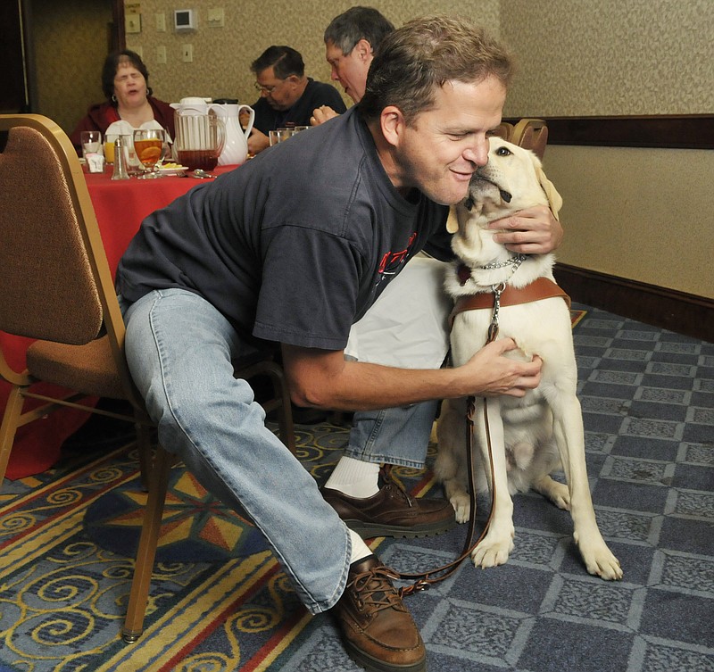 Melvin Smith pets his dog, Skyler, Friday at the Missouri Council of the Blind Convention at Capitol Plaza Hotel. Skyler is a 20-month-old trained yellow lab that has been with Smith for several months. The guide dog was trained in the state of California and is still adjusting to Missouri's noises and smells. Smith is a member of the Missouri Guide Dog Users and attended the annual convention.