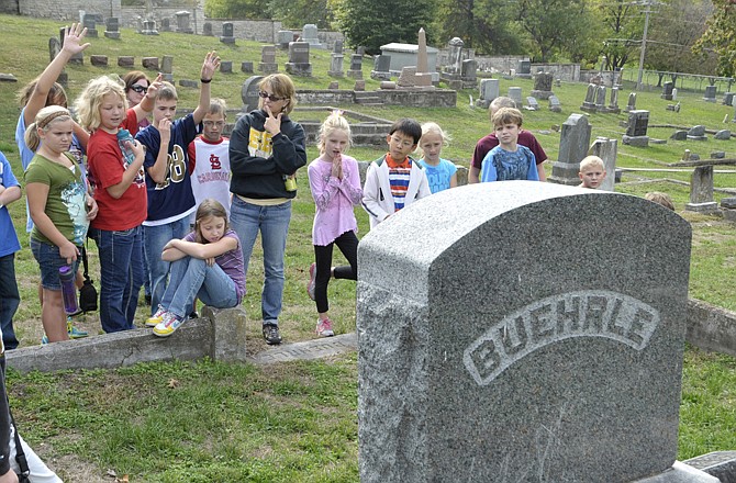 Ruthie Caplinger, background middle in black sweatshirt, asks questions of students as she explains information on a headstone before them. She teaches in the Jefferson City Public School district's EER class. 