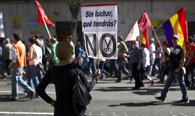 A woman holds a banner reading 'Without fighting, what would you get?' during a demonstration in Madrid, Spain, Sunday, Oct. 7, 2012. Thousands of people called by 150 organizations are marching in 56 Spanish cities to protest punishing austerity cuts they say will only increase unemployment and job insecurity.