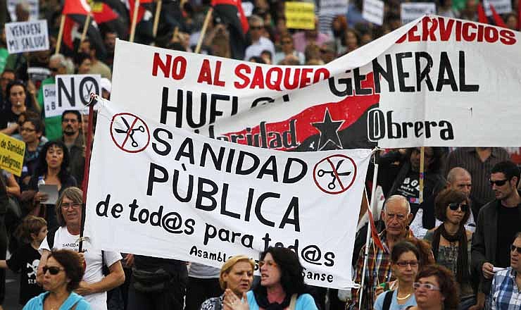Protestors hold a banner reading "public healthcare for everyone" and "general strike" as they march against healthcare austerity measures announced by the Spanish government and to defend the public healthcare system in Madrid, Spain, Saturday, Oct. 6, 2012. Hundreds of Spaniards concerned with government cuts to healthcare and civil servants hit with another freeze on their wages for next year held a protest in downtown Madrid.