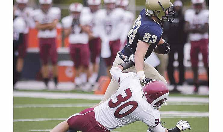 Helias' Hale Hentges shrugs off a tackle attempt by David Challoner of MIDCS during Saturday's game at Adkins Stadium.