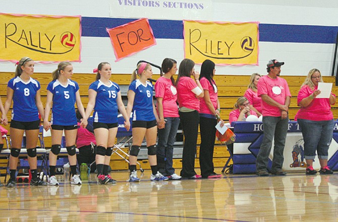 Members of the Russellville volleyball team stand with family and supporters during a rally to build a memorial to Riley Hudson, a 9-year-old racing fan whose mother used to coach the team.