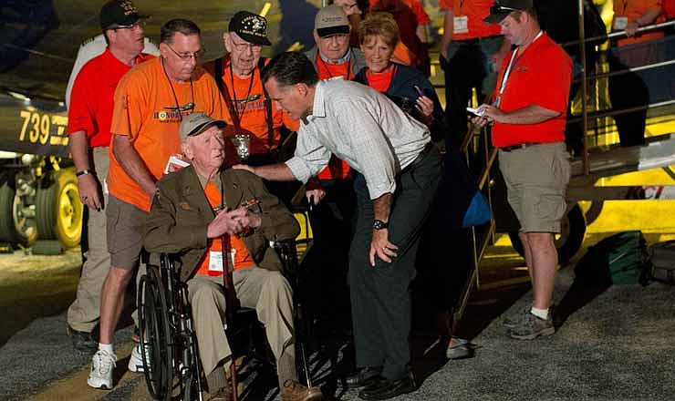In this Sept. 26, 2012, file photo Republican presidential candidate, former Massachusetts Gov. Mitt Romney shakes hands with World War II and Korean War veterans returning on an Honor Flight from Washington in Swanton, Ohio. Romney's road team scrambled to set up an impromptu meet-and-greet when his plane landed in Ohio at about the same time as an honor flight of aging veterans just back from visiting Washington memorials.