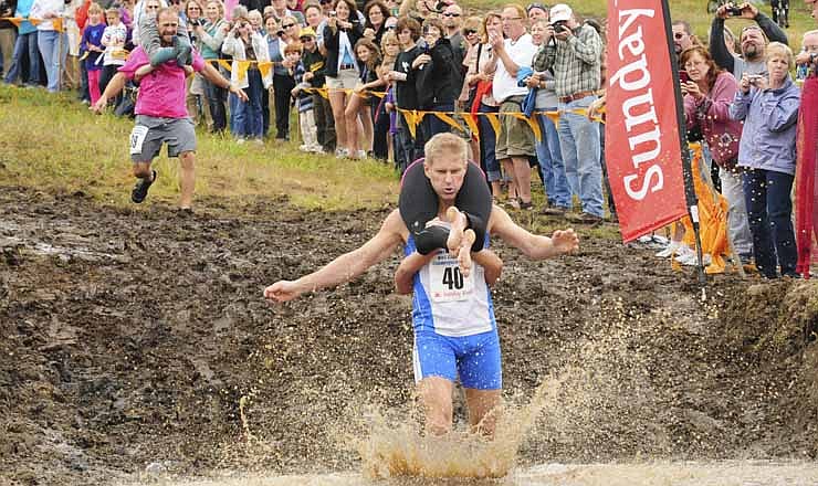 World Wife Carrying Champions Taisto Miettinen and Kristina Haapanen, from Helsinki, Finland, enter the water hazard just moments before second place finishers Jesse Wall and Christine Arsenault of South Paris during the finals of the 2012 North American Wife Carrying Championship Saturday, Oct. 7, 2012 at Sunday River in Newry, Maine. The Finnish duo took first place with a time of 52.58 seconds. "Against Taisto, we went in hand to hand, shoulder to shoulder and he got that big long leg in front of my stomach and I just couldn't quite get over it," said Wall of the first log hurdle on the course. "I got stuck there. We lost some time to him."