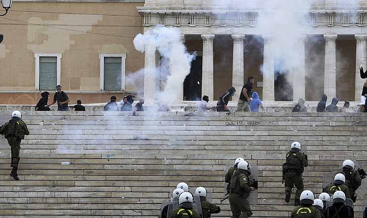 Protesters are chased by riot police during clashes in front of the parliament in Athens, Tuesday Oct. 9, 2012. German Chancellor Angela Merkel got a hostile reception from ordinary Greeks Tuesday when she flew into Athens on her first visit to the country since its debt crisis erupted three years ago. 