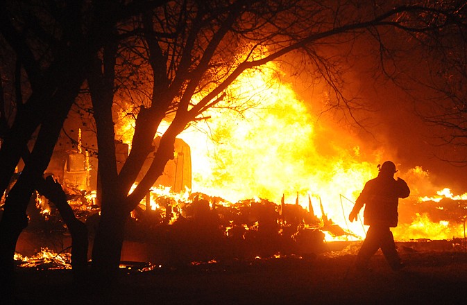 A firefighter examines the flames Wednesday as a fire sweeps through Bucyrus, N.D. Authorities say the wind-fueled wildfire all but destroyed the tiny southwestern North Dakota town, displacing all 27 residents. 