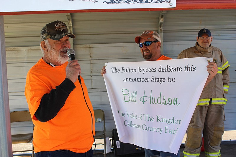Bill Hudson thanks the Jaycees while Kevin "Numie" Moreland presents him with a banner dedicating the announcer's stage to his name. "The voice of the Kingdom of Callaway County Fair" has volunteered his announcing skills to the fair and other events for 30 years, and will also serve as grand marshal for the Jaycee's Christmas parade.