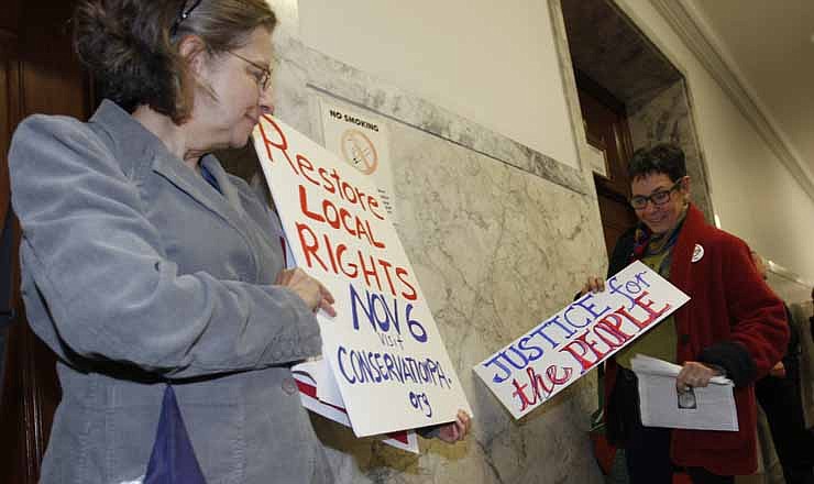 Cynthis Walter, left, with the Westmoreland Marcellus Citizens Group holds her sign with another woman after they left the Pennsylvania state Supreme Courtroom in Pittsburgh where the court was hearing arguments from seven municipalities challenging portions of a new law that regulates natural gas exploration on Wednesday, Oct. 17, 2012.
