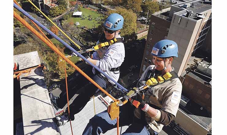 Sarah Moore, left, and Amy Smith of the Greene County Sheriff's Department get set to rappel 13 stories from the top of the Jefferson State Office Building in Jefferson City during Saturday's Over The Edge fundraiser benefiting Special Olympics Missouri.