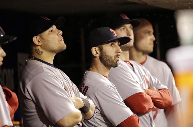 Cardinals teammates Yadier Molina (left) and Daniel Descalso watch from the dugout during the ninth inning of Monday night's game against the Giants in San Francisco.