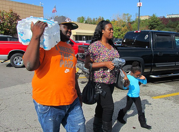 From left, Jimmy Mickens, Tiffany Shurland and Kelis Smith, 5, head back to their car after buying a case of bottled water at Walmart. Many stores were struggling to keep water in stock because of the skyrocketing demand.