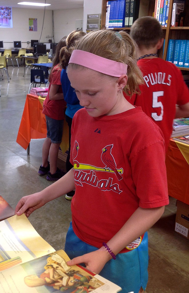 Anna Stubinger, fifth grader, checks out possible book purchases at the Russellville book fair.