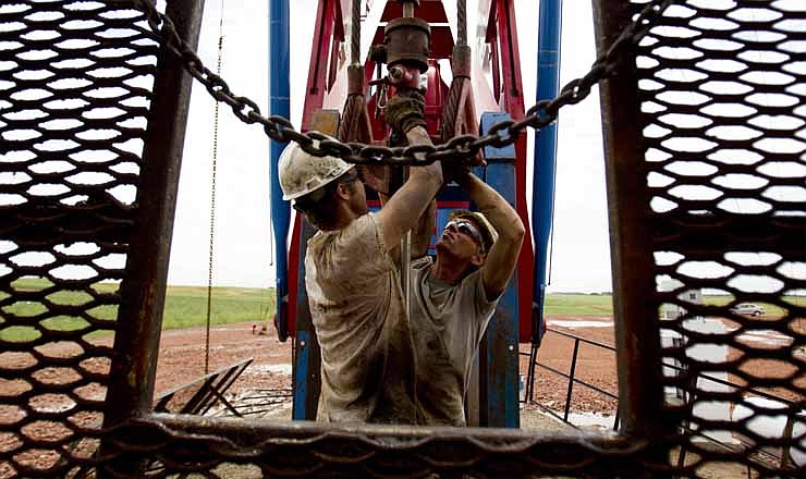 In this Tuesday, July 26, 2011 file photo, Austin Mitchell, left, and Ryan Lehto, work on an oil derrick outside of Williston, N.D. U.S. oil output is surging so fast that the United States could soon overtake Saudi Arabia as the world's biggest producer. U.S. production of oil and other liquid hydrocarbons is on track to rise 7 percent in 2012 to an average of 10.9 million barrels per day. It's the fourth straight year of crude increases, and this year drillers are on track to post the biggest single year gain since 1951.