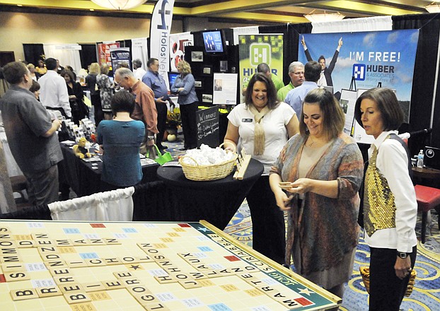 Stephanie Lehmen, foreground right, and Emily Mantle, third from right, both with JCMG, host Frances Boswell in a game of JCMG Scrabble on Thursday morning at the annual Jefferson City Area Chamber of Commerce Small Business Showcase at the Capitol Plaza Hotel. Theirs was one of more than 100 booths at this year's annual small business showing.