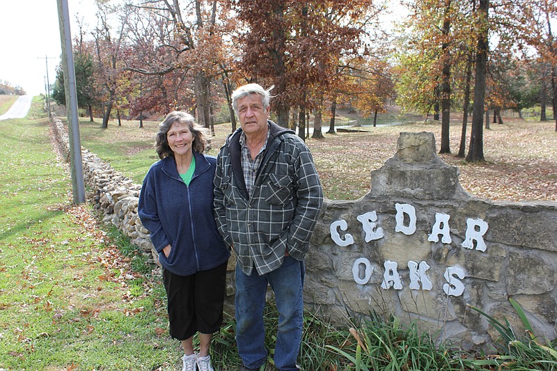 Linda and Eddie Kronk stand next to the Cedar Oaks sign and dry-stacked stone wall along their property off County Road 305. Over the past six years, Eddie Kronk has built the quarter-mile partition, similar to those found in Europe.