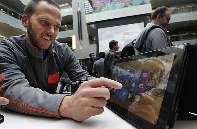 John Eversole, a marketing manager for Microsoft, uses a Samsung Series 7 Slate device with the new Windows 8 operating system during an event unveiling a new Microsoft Windows operating system Thursday, Oct. 25, 2012, at the company's headquarters in Redmond, Wash. Windows 8, attempts to bridge the gap between personal computers and fast-growing tablets with its touch-enabled interface. It is the most dramatic overhaul of the personal computer market's dominant operating system in 17 years.