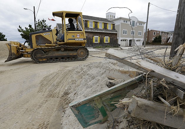 A worker responding to superstorm Sandy rolls a bulldozer Thursday past storm debris in Brant Beach, a community on Long Beach Island, N.J.