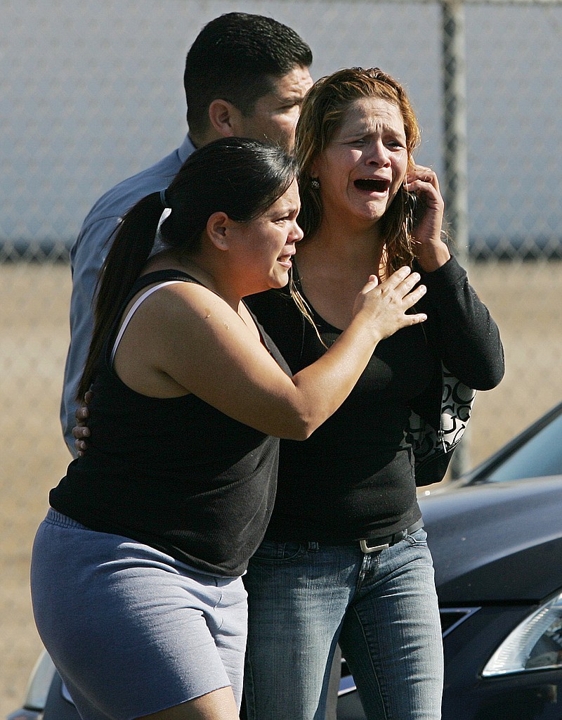 An unidentified woman cries as she's rushed into a car Tuesday after learning of a workplace shooting in Fresno, Calif. A parolee who worked at a California chicken processing plant opened fire at the business on Tuesday, killing two people and wounding two others, before shooting himself, police said. 