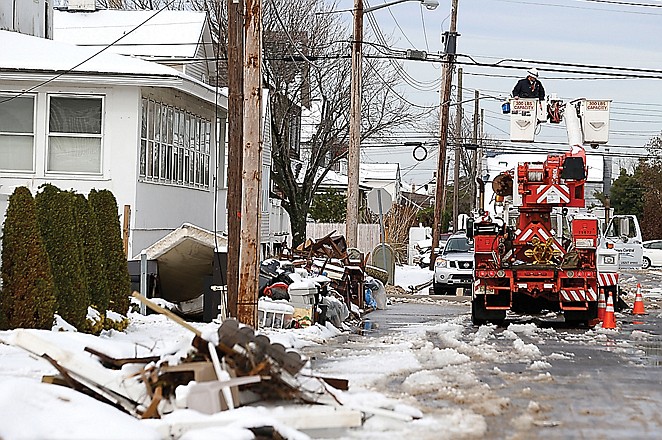 Utility workers check the power lines as snow-covered debris from Superstorm Sandy litters a street following a nor'easter storm in Point Pleasant, N.J.  