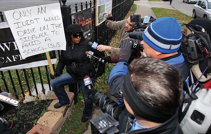 Shena Hardin talks to the media as she holds up a sign while serving a highly public sentence Wednesday in Cleveland. Hardin drove on a sidewalk to avoid a Cleveland school bus that was unloading children.