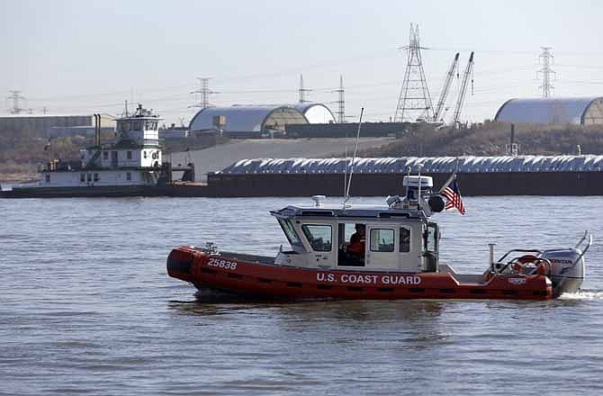 A Coast Guard boat patrols in the foreground as a barge makes its way down the Mississippi River on Friday, Nov. 16, 2012, in St. Louis.