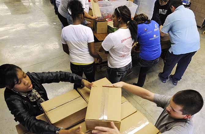 Zurett Meridith, left, and Ethan Meyr stack care packages as Operation: Guardian Angel volunteers fill the boxes with goodies on Saturday in Jefferson City.