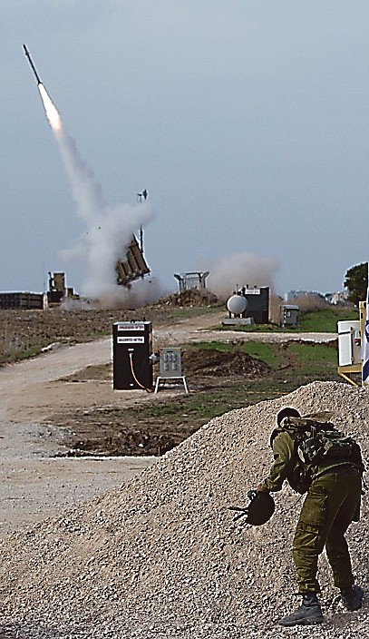An Israeli soldier watches an Iron Dome missile as it is launched to intercept a rocket fired by Palestinians militants.