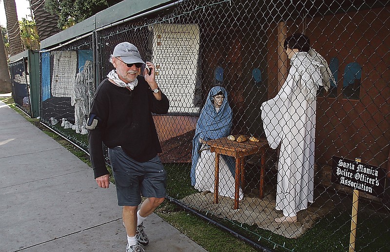 A man walks past two of the traditional Nativity scenes along Ocean Avenue at Palisades Park in Santa Monica, Calif. Avowed atheist Damon Vix, inset left, last year won two-thirds of the booths in the annual, city-sponsored lottery to divvy up spaces in the live-sized Nativity display.