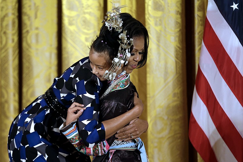 First lady Michelle Obama hugs Wu Lianyun, 13, of China, as she accepts the International Spotlight Award for China's The 100 Dong Songs Program on Monday in the East Room of the White House in Washington.