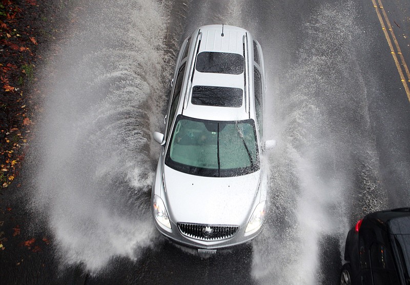 Heavy rains cause standing water near Montlake Boulevard NE at 25th Ave., slowing down vehicles heading toward Husky Stadium on Monday in Seattle. More Pacific storms that started rolling across the Northwest in waves over the weekend are on their way, according to the National Weather Service.