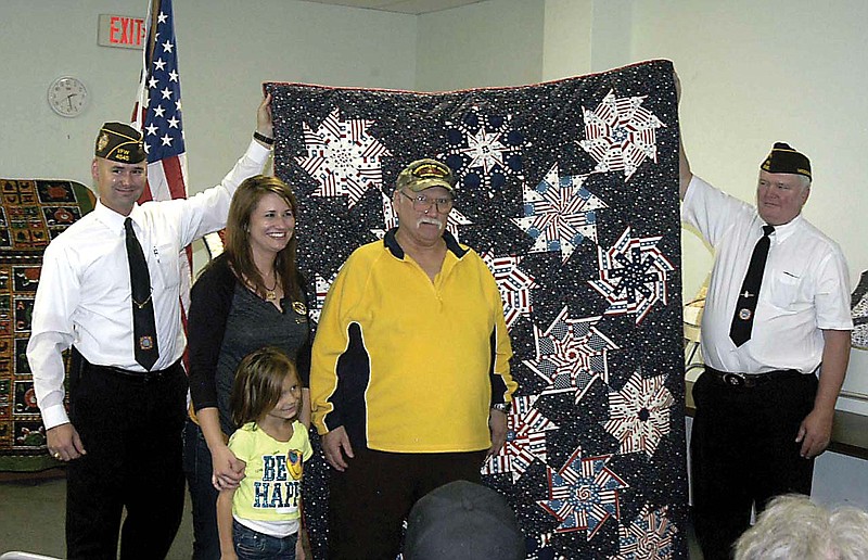 Veteran Phillip Sumpter, center, receives a Quilt of Valor, held by VFW Post 4345 Commander Kelly D. Messerli, left, and Past Commander Jim Hamilton, right. He was recommended for the honor by his niece by marriage, Carey Schoeneberg, in the photo with her daughter Avery. The quilt was by Judy Scott.
