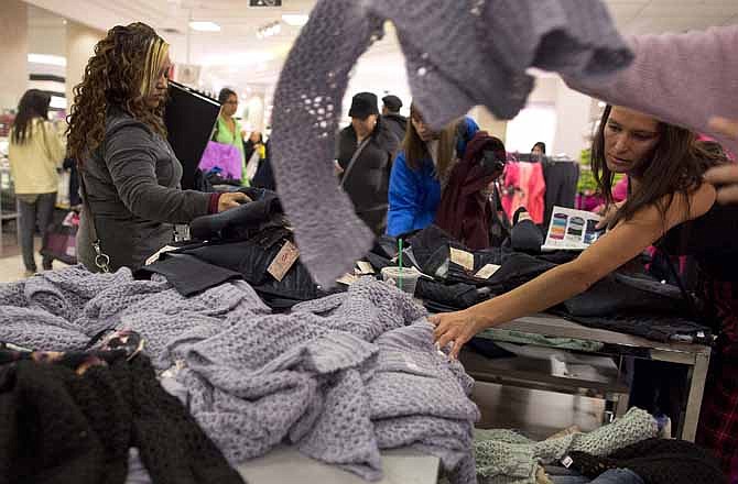 Shoppers rummage through a pile of sweaters on sale at a J.C. Penney store, Friday, Nov. 23, 2012, in Las Vegas. Despite a surge of resistance as the sales drew near, with scolding editorials and protests by retail employees and reminders of frantic tramplings past, Black Friday's grip on America may be stronger than ever.
