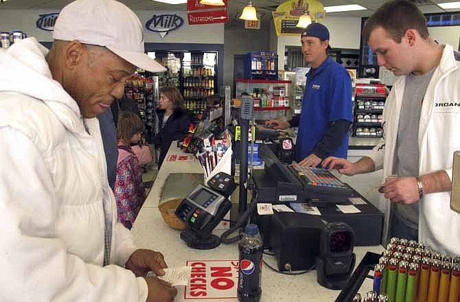 Michael Arrington, left, buys a Powerball ticket from cashier Lee Heilig, right, on Friday, Nov. 23, 2012, at a DeliMart convenience store in Iowa City, Iowa. The jackpot had reached $325 million as of Friday.