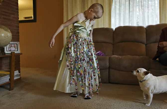 Mykayla Comstock, 7, one of Oregon's youngest medical marijuana patients, admires her dress while her dog, Chase, looks on Nov. 2, 2012. The dress was made for her by a family friend. The dress contains 1,000 folded origami paper cranes. The crane folding holds cultural significance in Japan, where the gesture of folding and offering that many cranes to someone symbolizes prayers or well wishes to the recipient.