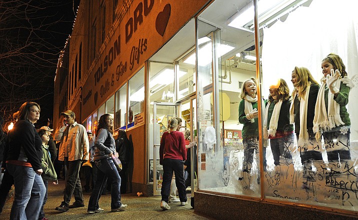 Russellville Girl Scouts from Troop 70222 wave to the passing crowd after performing a routine Friday night in the window at Tolson Drug during the annual Living Windows event in downtown Jefferson City.