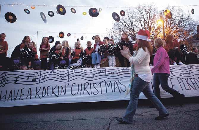 Participants of the Jefferson City Jaycees 2012 Christmas Parade wave and smile to the crowd Saturday evening. The theme for the parade this year was Rock and Roll Christmas.