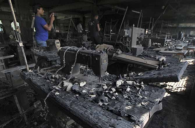 In this Monday, Nov. 26, 2012 file photo, a man takes photographs inside a burned out garment factory on the outskirts of Dhaka, Bangladesh. The blaze at the factory killed 112 workers.