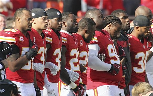 Kansas City Chiefs players stand arm-in-arm during a moment of silence before Sunday's game against the Carolina Panthers at Arrowhead Stadium.