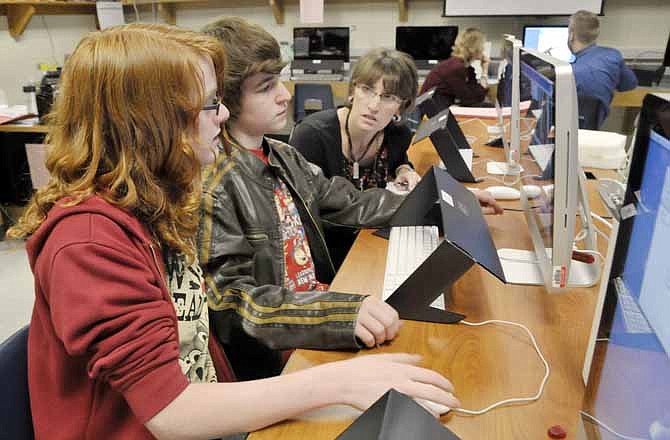 Ben Cook, near, and Aidan Gallagher demonstrate to seventh grade teacher Karen Distler what they have learned about creating movies on their computer using the iMovie application. (News Tribune file photo)