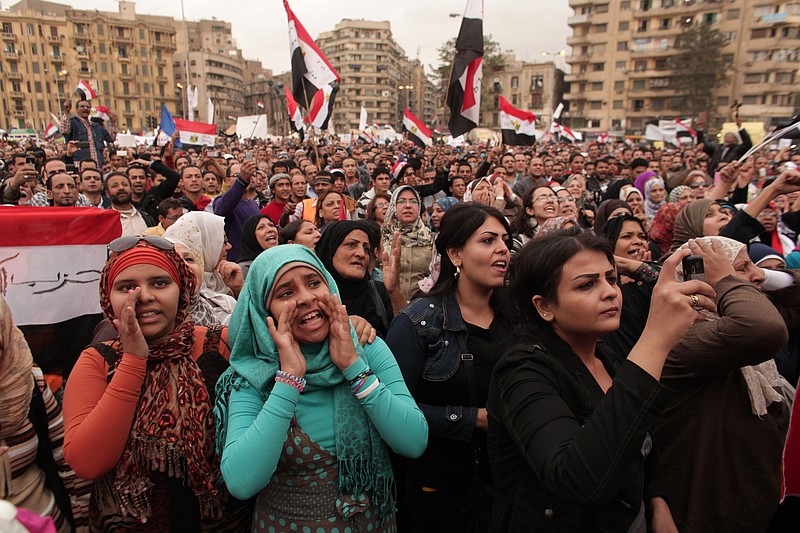 Protesters chant slogans and wave national flags Tuesday in Tahrir Square in Cairo, Egypt. Hundreds of black-clad riot police deployed around the Itihadiya palace in Cairo's district of Heliopolis. Barbed wire was also placed outside the complex, and side roads leading to it were blocked to traffic.